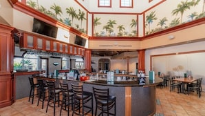 A bar area with a counter, bar stools, and a seating area with tables and chairs. - Ev7861ha - Regal Palms Resort & Spa - 4 Bed 3 Baths Townhouse (Davenport)