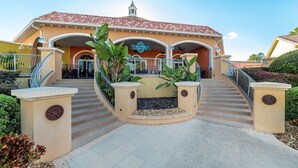 A hotel entrance with a curved staircase, a central planter, and a sign above the entrance. - Ev7861ha - Regal Palms Resort & Spa - 4 Bed 3 Baths Townhouse (Davenport)
