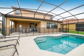 A pool area with a glass enclosure, outdoor seating, and a building with a tiled roof. - Ev8081ha - Providence - 5 Bed 5 Baths Villa (Davenport)