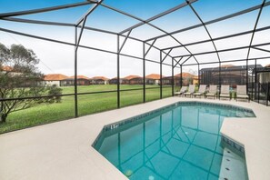 A swimming pool with a glass enclosure, surrounded by lounge chairs and a view of distant hills. - Ev8081ha - Providence - 5 Bed 5 Baths Villa (Davenport)