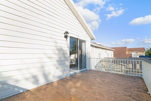 A white building with a covered patio area and a sliding glass door leading to an interior space.