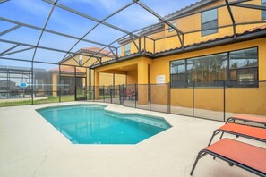 Ein Poolbereich mit Glasveranda, Sitzgelegenheiten im Freien und einer gelben Gebäudefassade.