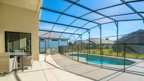 Ein überdachter Patio-Bereich mit Pool, Gartenmöbeln und Blick auf benachbarte Häuser.