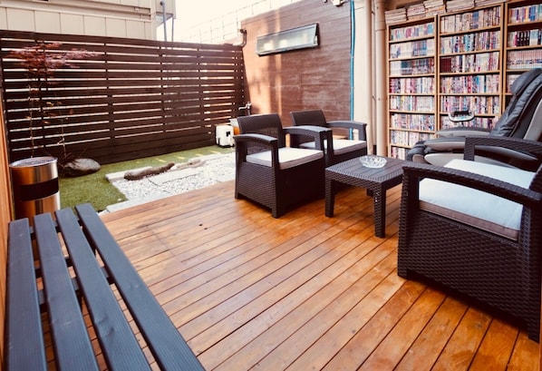 Relax in a serene outdoor space with a wooden deck, wicker chairs, and a small table.