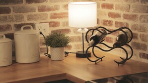 A kitchen counter with a white lamp, a potted plant, and two white containers.