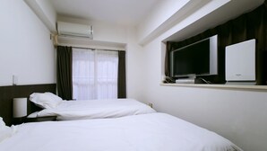 A hotel room with two single beds, a TV, and an air conditioning unit. - Hostel 758 Nagoya 2A (Nagoya)