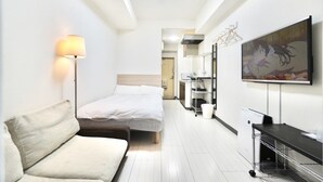 A hotel room with a bed, a sofa, a TV, and a kitchenette. - Hostel 758 Nagoya 1P (Nagoya)