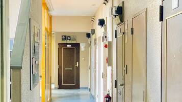 A corridor with doors on both sides, a fire extinguisher, and a door labeled "1K".