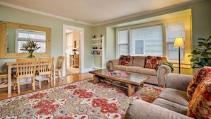 A living room with a sofa, coffee table, and a dining area with chairs and a table. - Peaceful Wine Country Getaway - Walk to Downtown! (Walla Walla)
