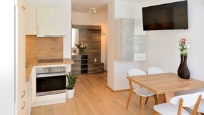 Eine moderne Küche mit weißen Schränken, einem eingebauten Ofen und einem Essbereich mit einem Holztisch und weißen Stühlen.