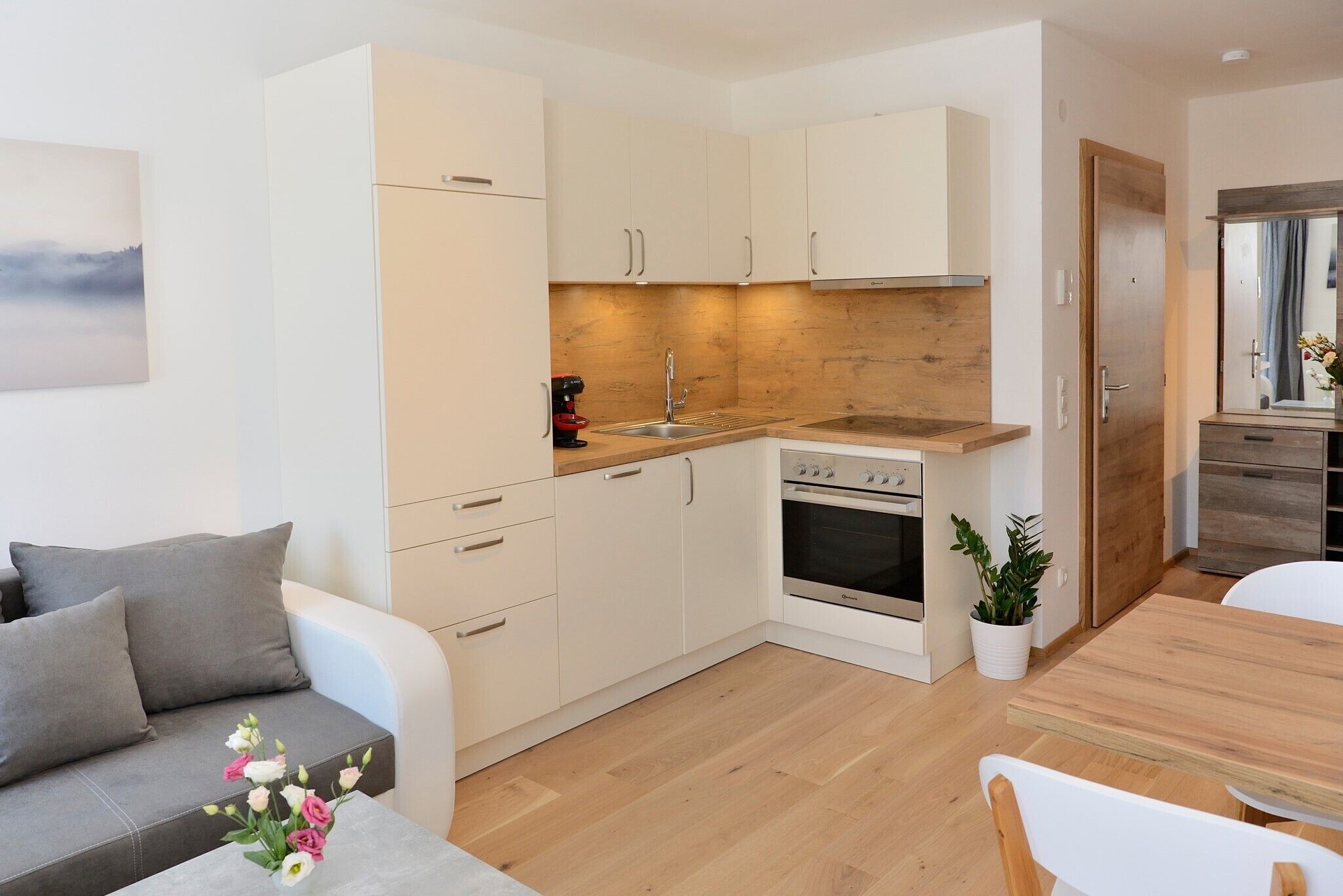 A compact kitchen with a stove, sink, and wooden countertop. There is a dining area with a table and chairs.