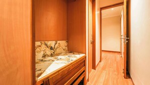 Una camera d'albergo con un armadio in legno, una panca rivestita in marmo e un pavimento in legno.