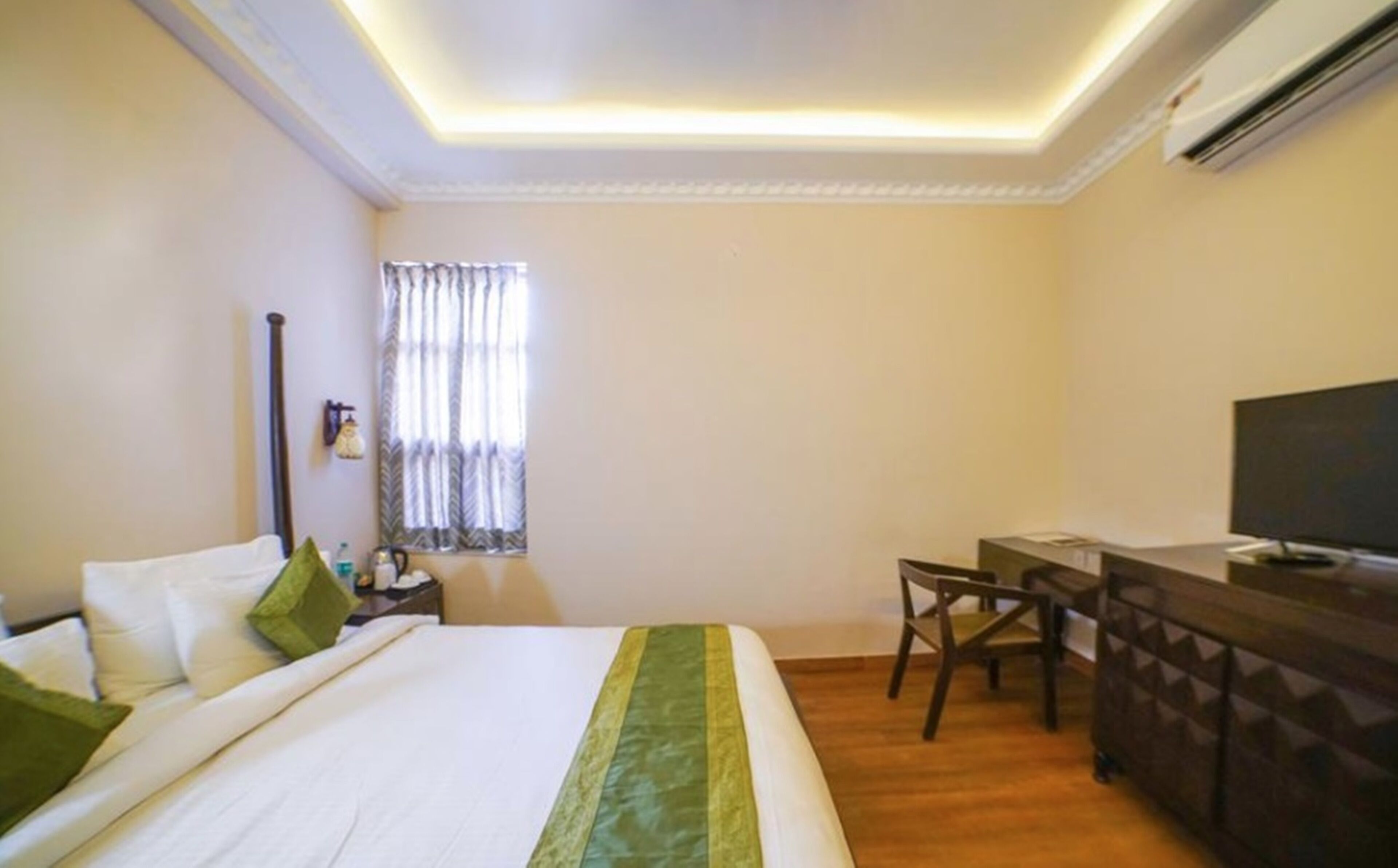 A hotel room with a bed, a desk, a chair, and a television.