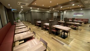 A modern dining area with wooden tables and benches, recessed ceiling lighting, and a neutral color palette. - Hotel Route Inn Sakurai Ekimae (Sakurai)
