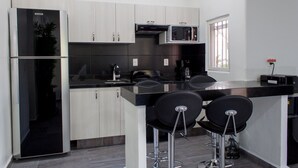 Een moderne keuken met een koelkast, magnetron en barstoelen.
