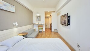 Habitación de hotel con cama, una pequeña mesa, sofá, escritorio y espejo.