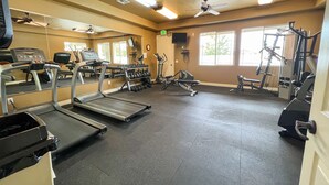 Une salle de sport équipée de tapis de course, de vélos elliptiques et de matériel de musculation.