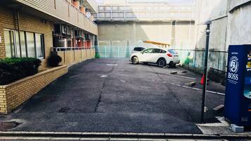 A parking area with a white car and a blue vending machine labeled 'Sutory Coffee Boss'.