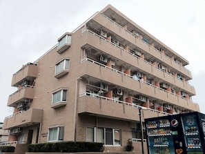 A multi-story residential building with balconies, a vending machine, and a visible sign. - Hostel 758 Nagoya3P (Nagoya)