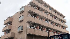Un immeuble en briques à plusieurs étages, doté de balcons, de climatiseurs et d’un distributeur automatique.