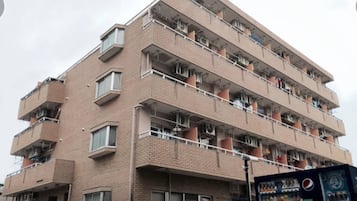 A multi-story brick building with balconies, air conditioning units, and a vending machine.