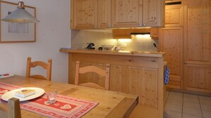 Eine Küche mit Holzausstattung, einem Esstisch mit Stühlen und Pendelleuchten.