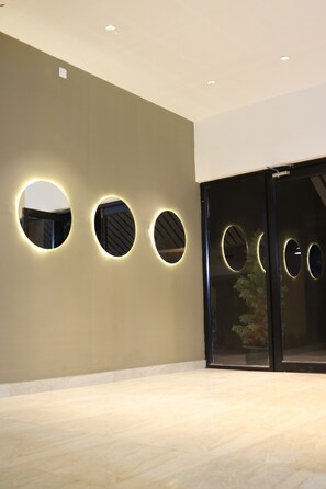 A modern interior with circular light fixtures on a wall and a glass door. - Sweven Stays (Mangaluru)