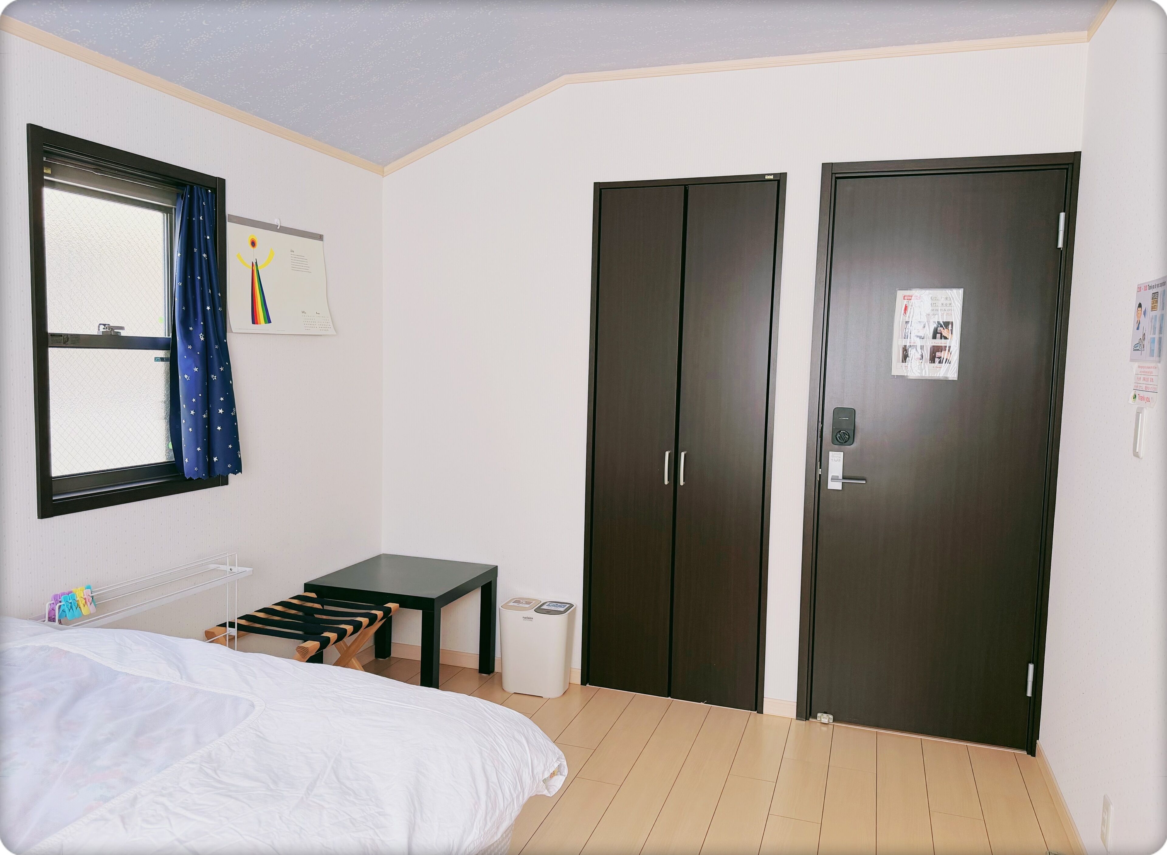 A bedroom with a bed, a desk, a wardrobe, and a window with curtains.