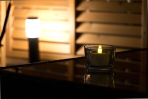 A candle in a glass holder on a reflective surface, with a bright light source in the background. - Mini Hotel Shinjuku Front 101 (Tokyo)