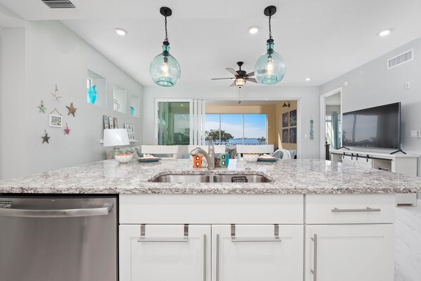 A modern kitchen with a large island, stainless steel appliances, and pendant lighting. - Exclusive Anna Maria Sound Waterfront Retreat with Shared Pool & Sunset Serenity (Bradenton)