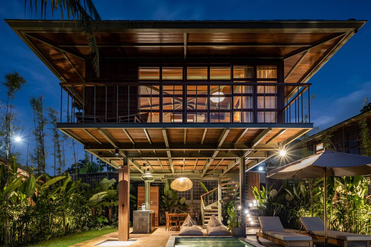 Ein modernes, zweistöckiges Haus mit Balkon, einer Treppe und einem Poolbereich.