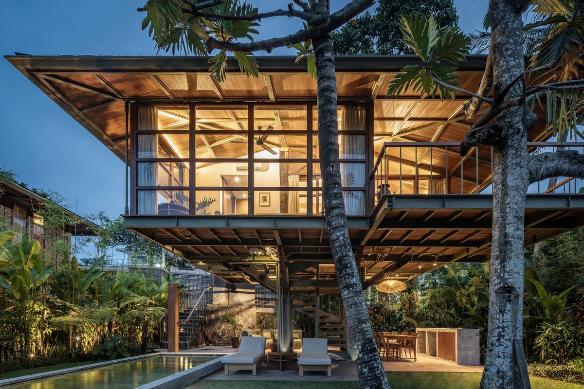 Ein modernes Haus mit Glasfassade, Sitzgelegenheiten im Freien und einem Pool.