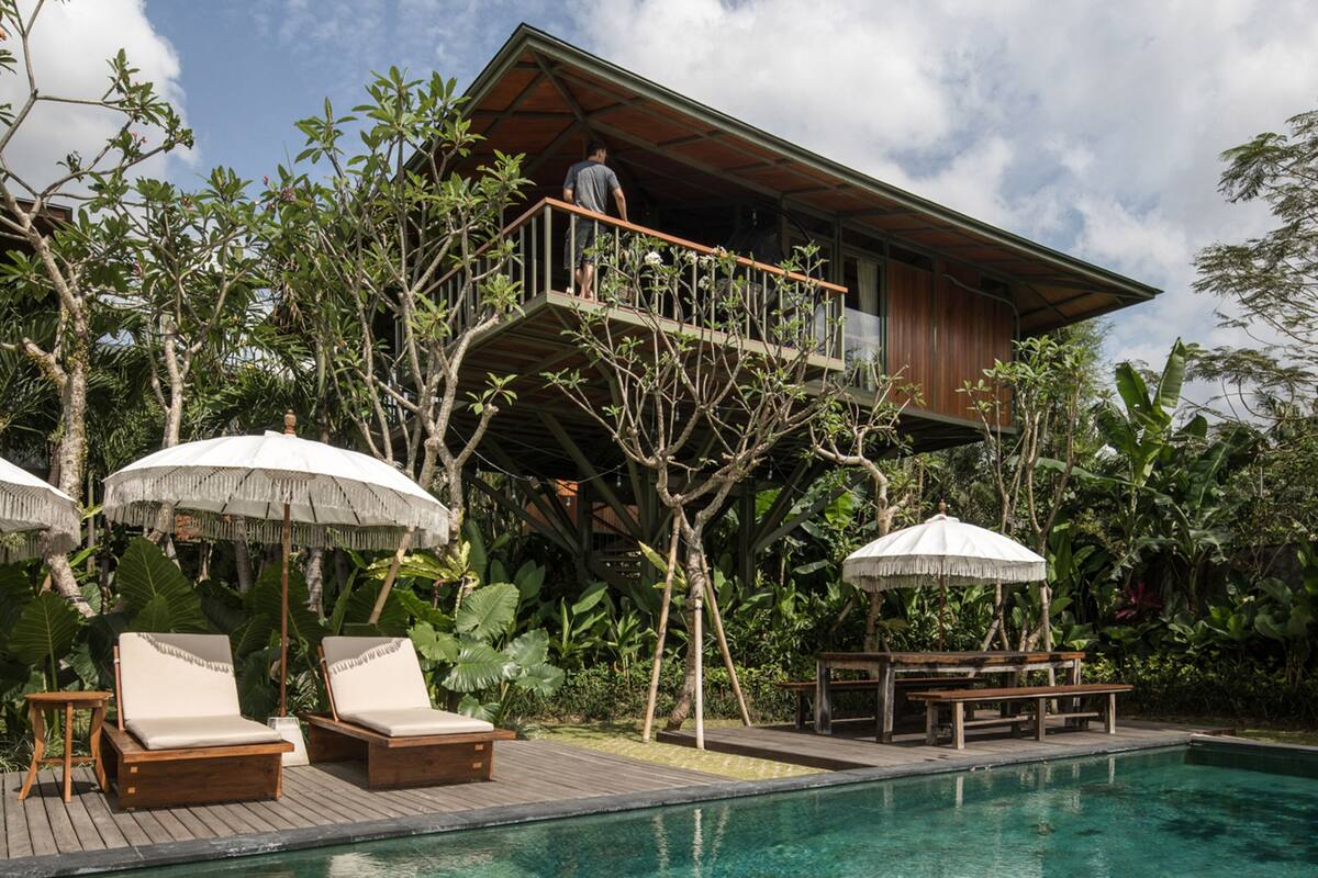 Ein Resort mit Pool, Liegestühlen und einem Holzhaus mit Balkon mit Blick auf den Pool.