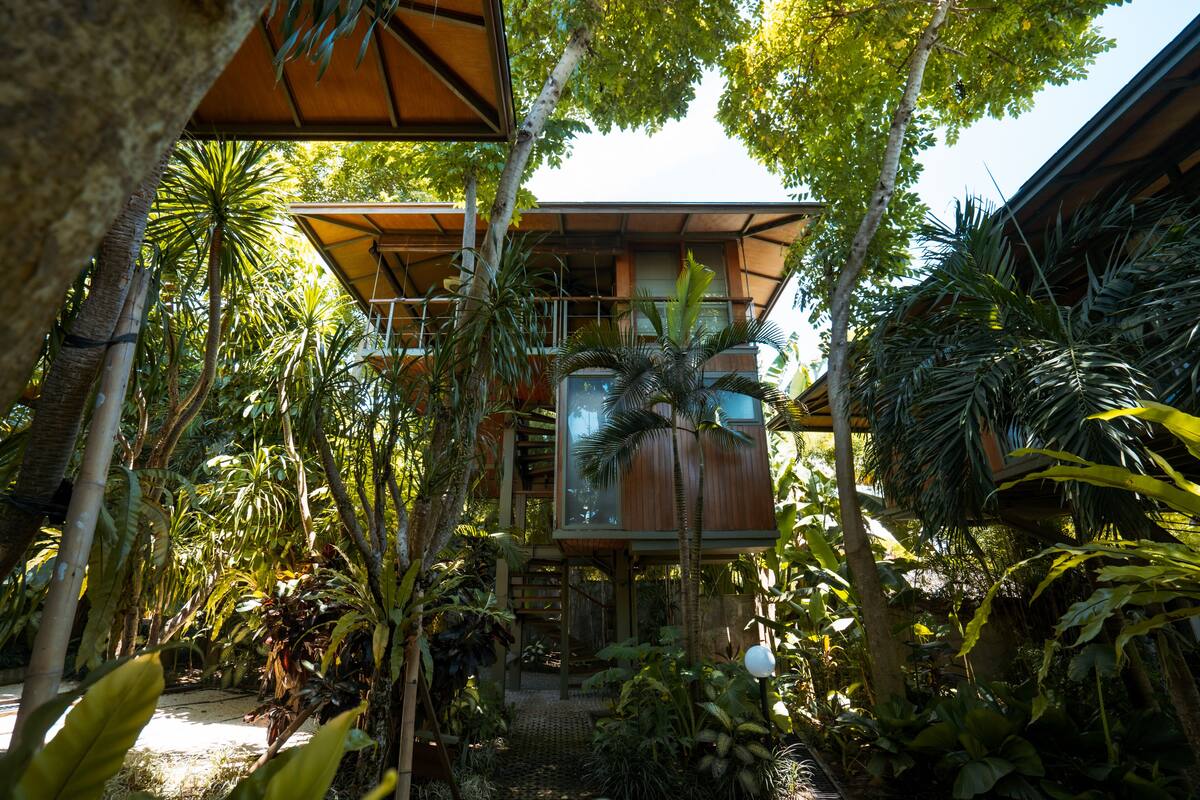 Ein modernes Haus mit Holzfassade, umgeben von üppiger tropischer Vegetation.