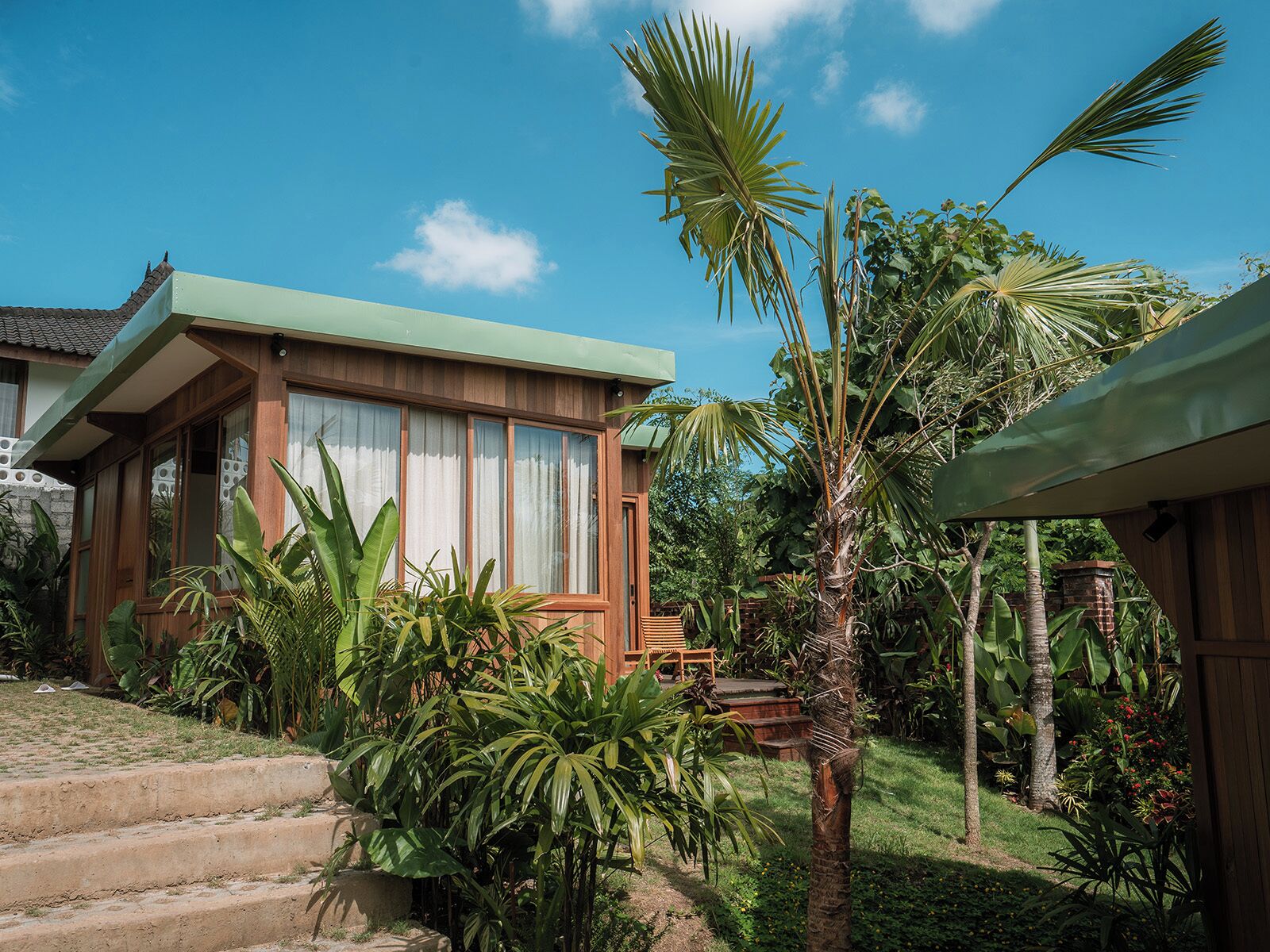 Una casa moderna con un ventanal grande y una escalera que lleva a la entrada.