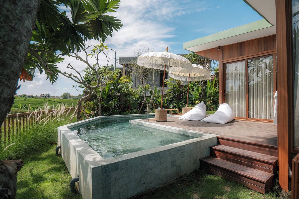 Ein moderner Poolbereich im Freien mit Whirlpool, Liegestühlen und einer Holzterrasse.