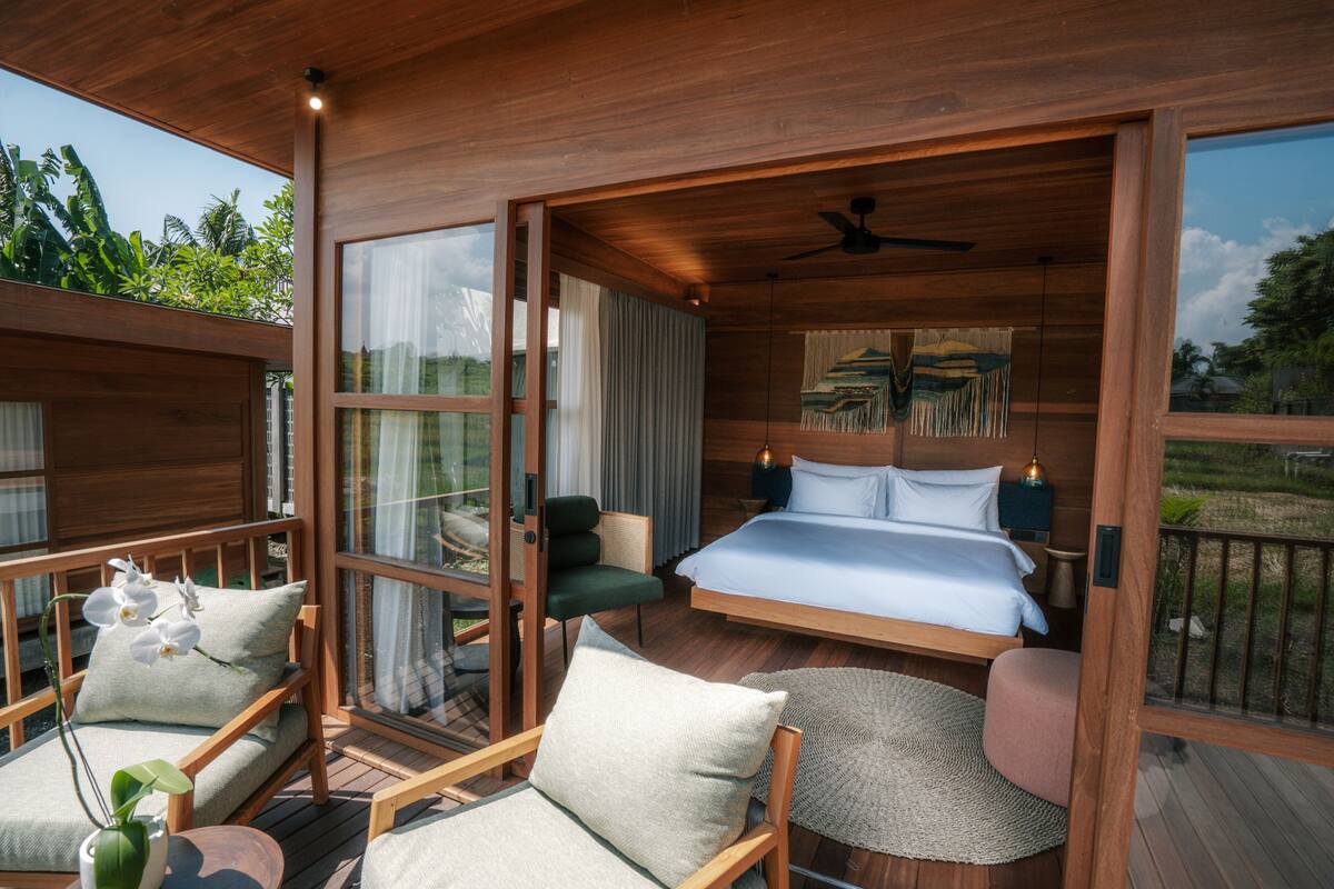 Ein geräumiges Schlafzimmer mit einem großen Bett, einer Sitzecke mit Sesseln und Blick ins Freie.
