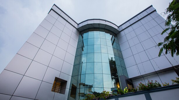 A modern building with a curved glass facade and a grid-like exterior. - Woodside Residency Thekkady (Peermade)