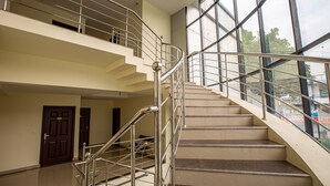 A multi-level interior with a central staircase, glass railings, and doors leading to different areas. - Woodside Residency Thekkady (Peermade)