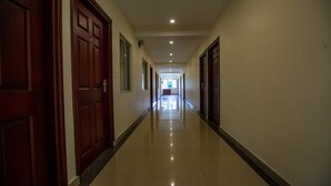 A corridor with wooden doors and windows, leading to a room with a view. - Woodside Residency Thekkady (Peermade)