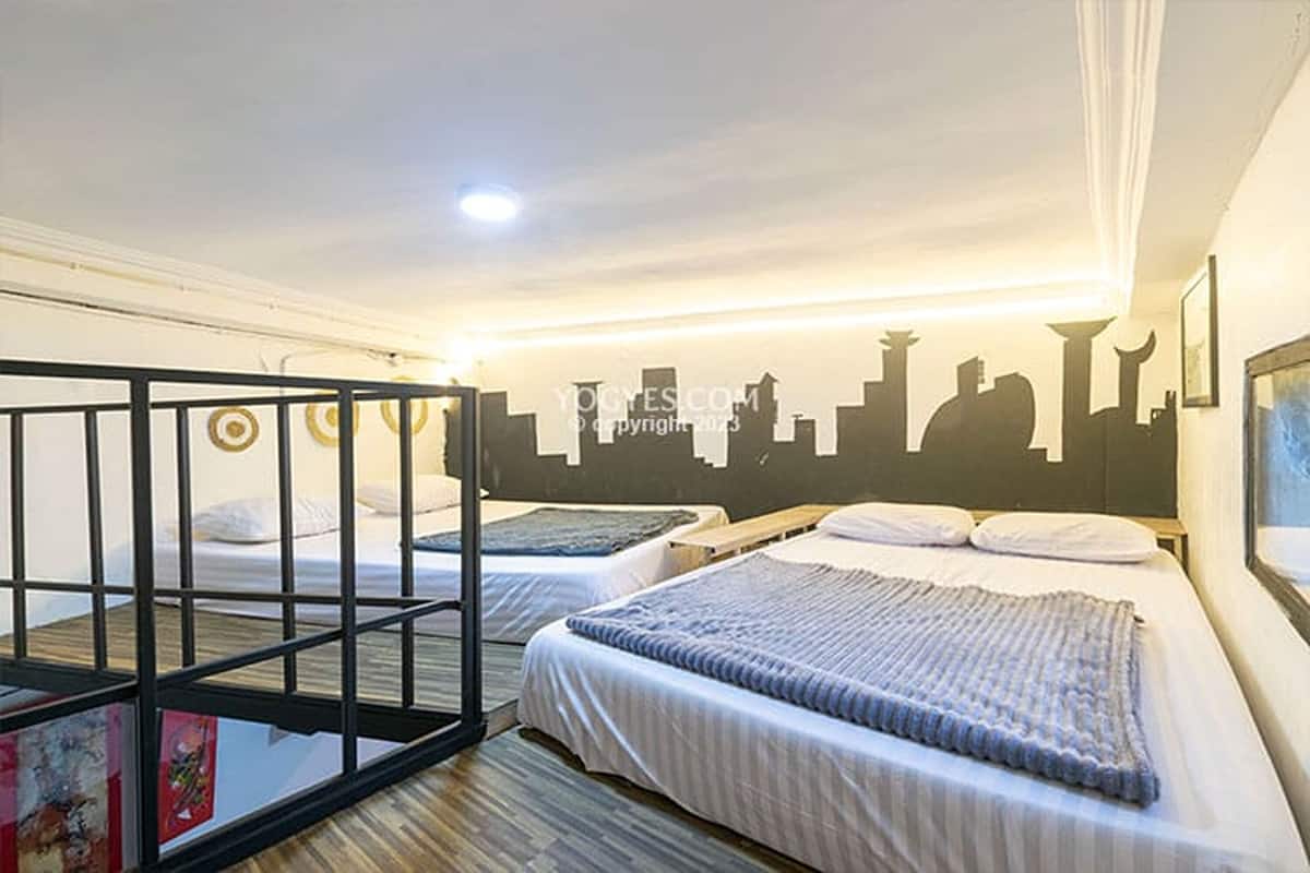 Une chambre d’hôtel avec deux lits, une fresque représentant le panorama de la ville sur un mur, et un balcon avec une balustrade.
