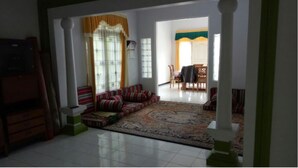 Uma sala de estar espaçosa com um sofá grande, um tapete estampado e uma área de jantar ao fundo.