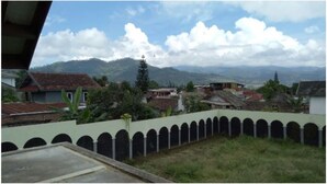 Zona residencial com casas, cerca verde e montanhas ao fundo.