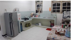 Cozinha compacta com geladeira, pia e pequeno espaço de jantar com mesa posta para dois.