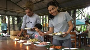A group of people dining at an outdoor restaurant with various dishes on plates. - Tegal Dukuh Camp (Taro)