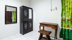 A room with a wooden wardrobe, a small wooden table with a bench, a mirror, and a green curtain with cartoon characters. - Kos VIP Josh (Pogung Lor)