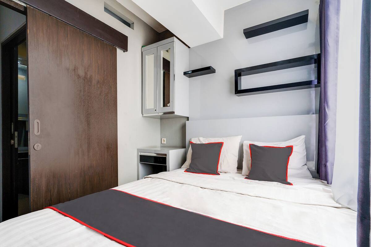 Een hotelkamer met een bed, een kledingkast, een bureau en een spiegel.