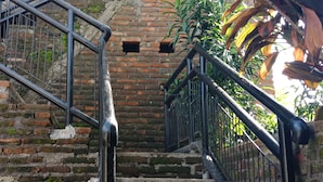 A staircase with metal railings leading to a wooden door. - Cheap Inn - Hostel (Banyuwangi)