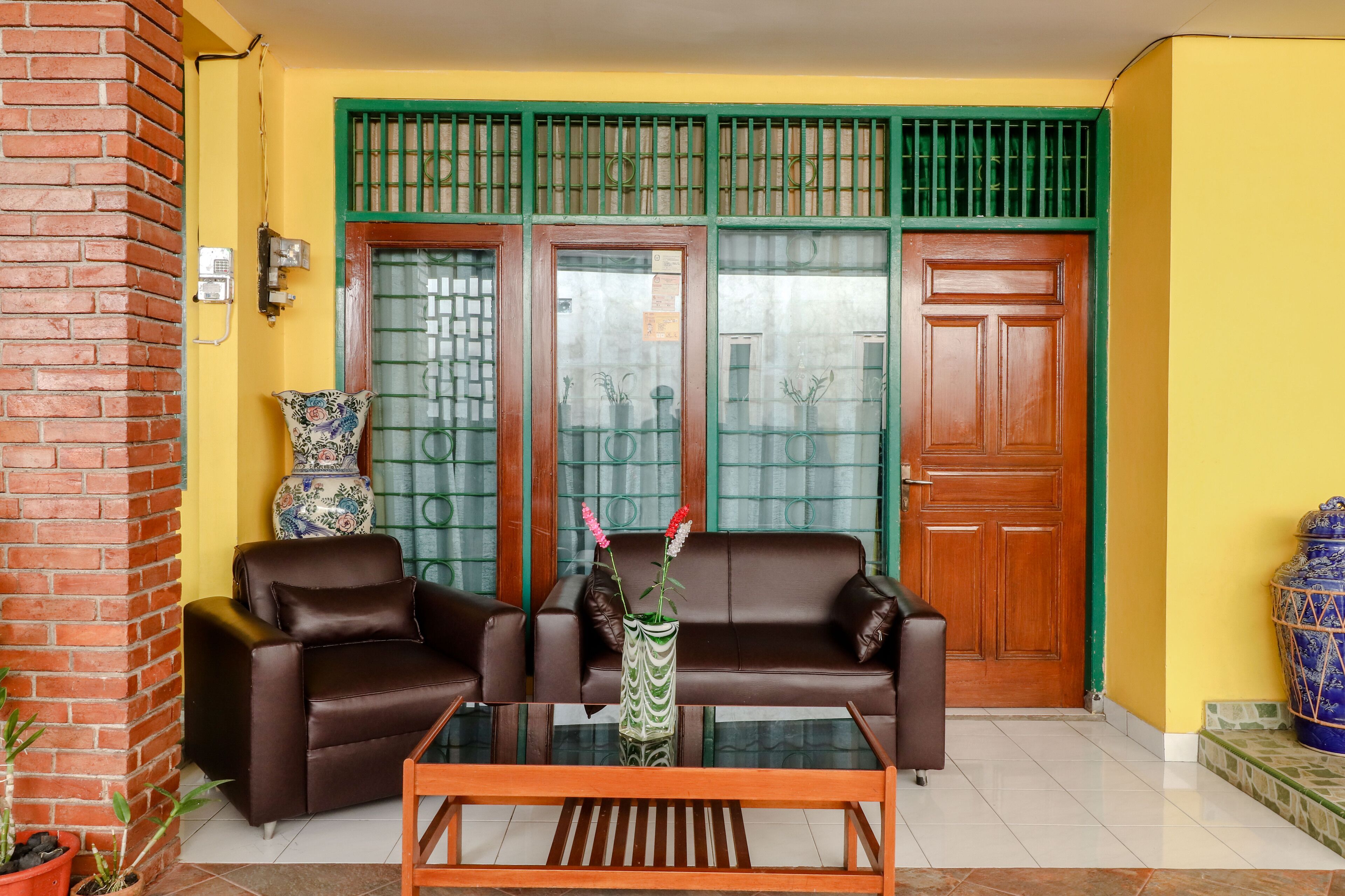 A living room with two brown sofas, a glass coffee table, and a decorative vase with flowers.
