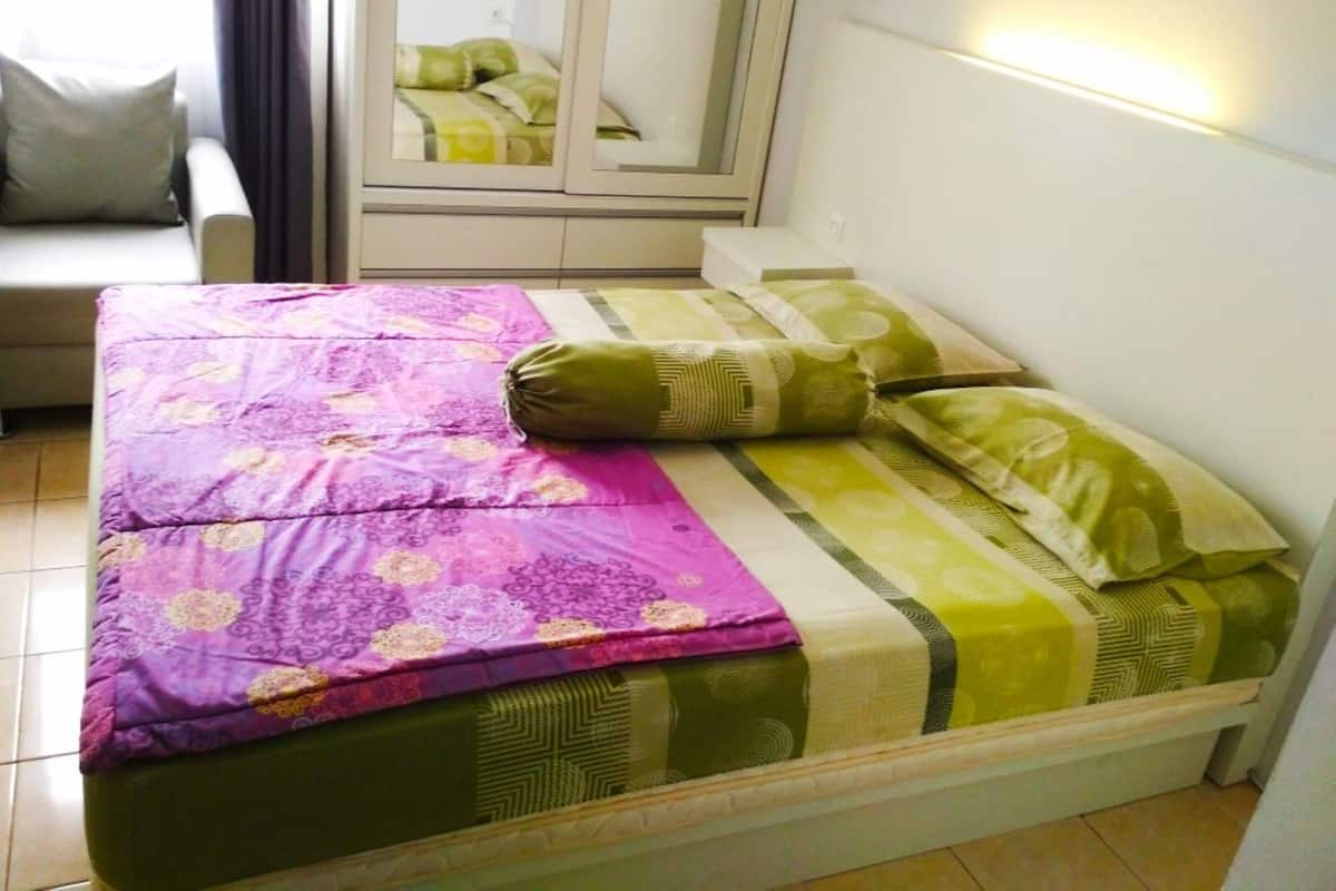 Una cama con colcha estampada, almohadas y cabecera.